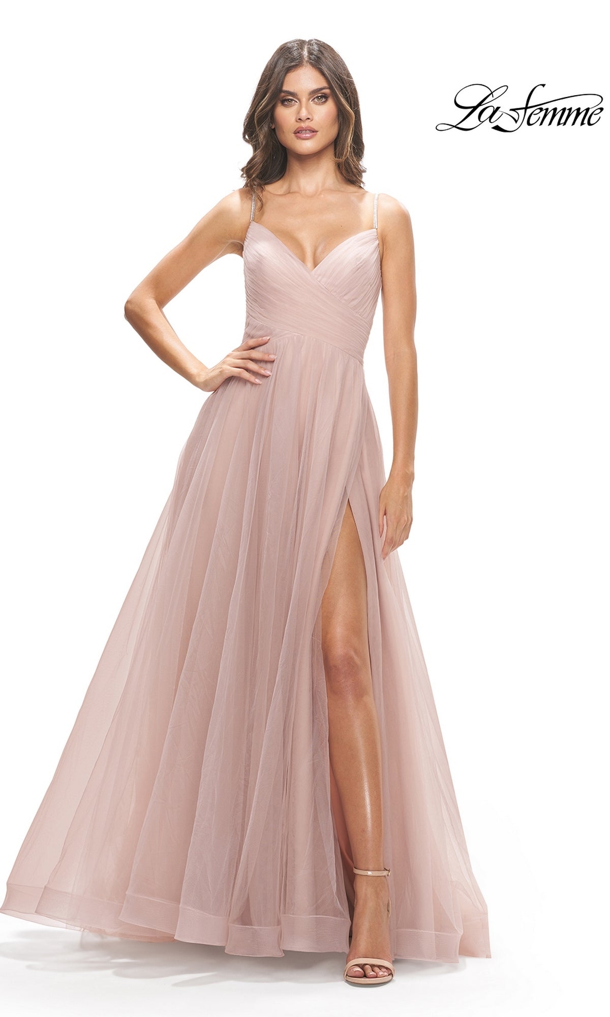 Woman wearing a blush pink La Femme A-Line Long Tulle Prom Dress 31204, featuring spaghetti straps, a fitted bodice, and a high slit, elegantly posing against a white background.